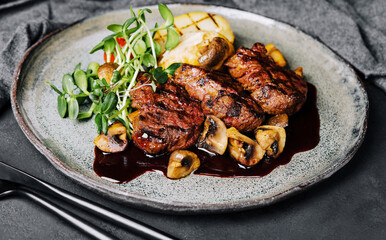 Rare roasted thick juicy beef fillet medallion topped with braised mushrooms and seasoned with fresh herbs