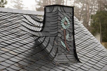 Detailaufnahme eines Kunstvoll mit Schieferschindeln gedeckten Daches mit  Esse - Zeugnis großer Dachdeckerkunst - Das Handwerk des Schieferdachdeckers  ist ein eigenständiger Berufsstand   