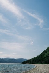 High-angle shot of the mountains and the sea under the sun light in the cloudy sky.