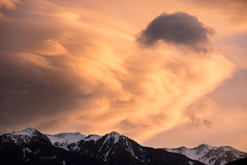 uno splendido tramonto in montagna con nuvole di forma particolare ed arancioni intense