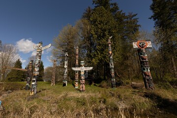 Obraz premium two totem poles next to a river with trees in the background