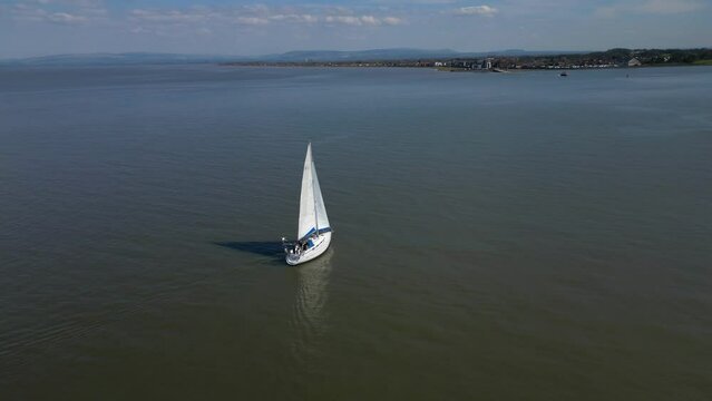 Yacht on calm sea nearing land at Knott End Wyre Estuary Fleetwood Lancashire UK
