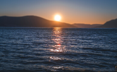 Beautiful sea sunset. A ball of sun setting in the hills. Focus on the surface of the water