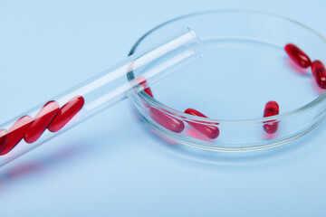 Science. Pharma business. Pharmaceutical industry. Medicine and clinical research cocnept. Translucent gel capsules in test tube and Petri dish, isolated on blue background with copy advertising space