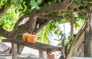Two coconut drinks on a wooden table by the sea