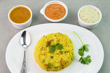 Rava kichadi in a plate served with sambar and chutney.