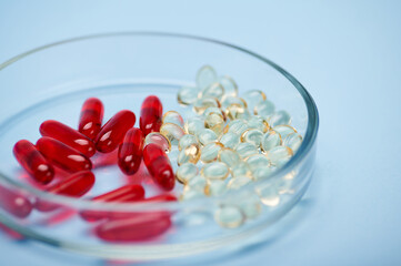 Red and gold color translucent gel capsules with fat solubles vitamins D and E, Omega-3 or fish oil...