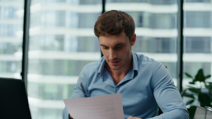 Excited man reading financial report sitting office close up. Manager rejoicing.