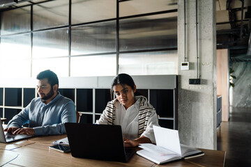 Indian business people working on laptops in modern office space