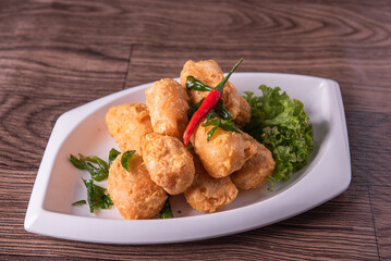 vegan deep fried golden beancurd tofu in salted egg yolk curry leaf pumpkin cream chilli vegetable on wood table asian chinese appetiser snack banquet halal food menu for restaurant