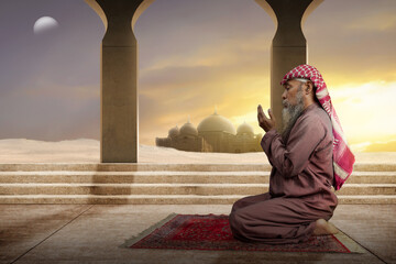 Muslim man with a beard wearing keffiyeh with agal in praying while raised hands