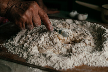 close-up of hands kneading dough with a spoon on the table in their home kitchen