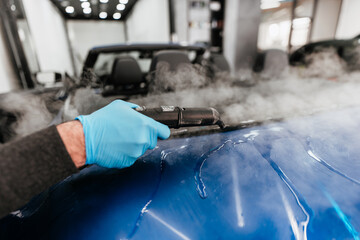 Professional vehicle detailing service in a modern car workshop. Car workshop specialist putting...