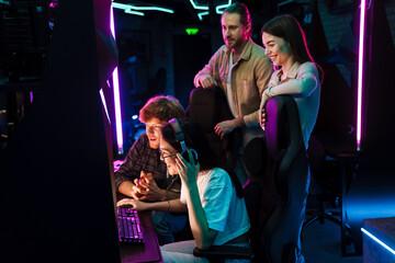 Group of people watching their friend playing video game in cybersport club