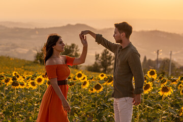 Fototapeta premium Young couple of lovers dancing in a sunflowers field, be my valentine and dnace a tango with me