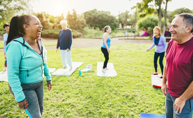 Senior people talking after yoga class outdoor at city park - Elderly lifestyle and multiracial concept - Main focus on right man face