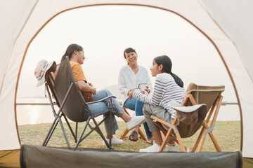 Asian family resting front of outdoor camping trip. Asia mother and two daughter playing ukulele together  - 591447801