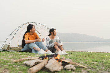 Campfire. Asian two teen woman talking while sitting on grass ground 