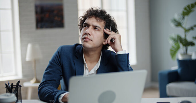 Hmm, need to think. Thoughtful confused asian man scratching head having doubts, not sure contemplating with uncertain puzzled face. Asian businessman at team meeting with his employees. 