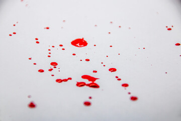 Red splashes of paint drops on a white background close-up	
