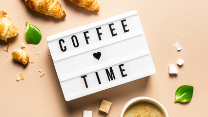 Eine weiße Tafel mit dem Text Coffee time, frische Croissants und eine Tasse Kaffee. Frühstück.