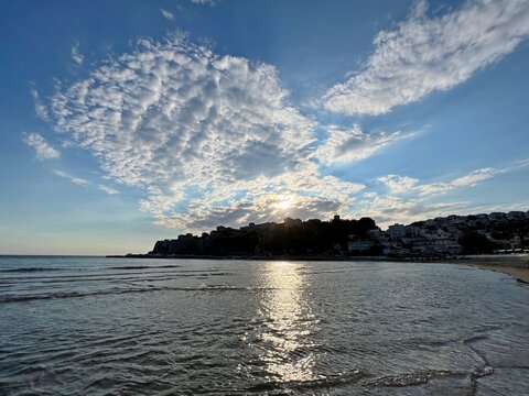 Sky clouds over the sea shiny silver water and old town.