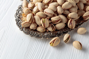 Salted pistachios on a white wooden table.