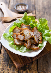 Delicious fried pork in a white plate on a wooden chopping board