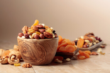 Obraz na płótnie Canvas Dried fruits and nuts on a beige ceramic table.