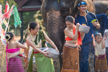 Tourist Asian people wearing traditional Thai dresses are happy to play splashing water during Songkran festival for travel a funny happy holiday in popular culture Thailand.