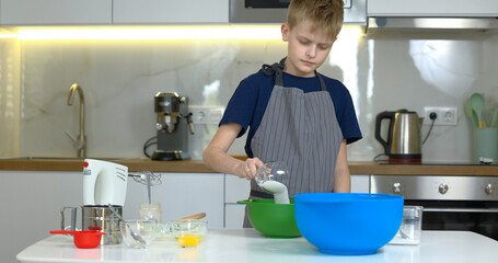 Young boy preparing dough for cookies on the kitchen alone.