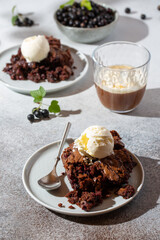 Chocolate brownie with blackcurrant on gray background. Homemade cake served with vanilla ice-cream and coffee.