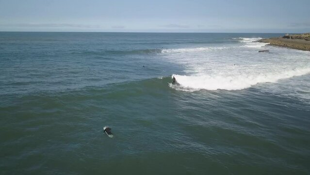 surfer riding a perfect barrel wave in the blue waters of Coxos, Ericeira, with aerial view of the rocky coastline.