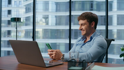 Naklejka na ściany i meble Smiling man reading good news mobile phone office closeup. Businessman laughing