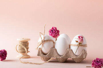 Composition with Easter eggs and eco-decor of dried roses on a beige background. Happy Easter
