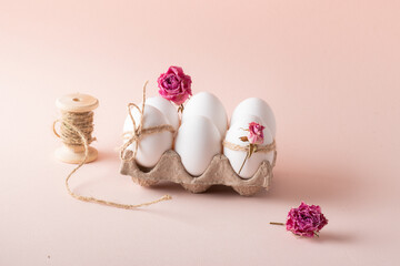 Composition with Easter eggs and eco-decor of dried roses on a beige background.