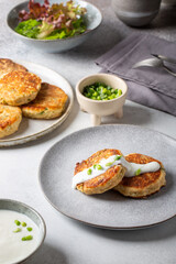 Greek zucchini fritters Kolokithokeftedes on gray background. Zucchini pancakes with feta and herbs, served with greek yogurt.