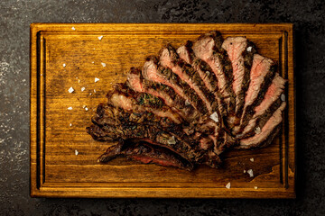 Sliced boneless ribeye steak served on a wooden board in a restaurant