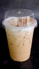 Iced coffee in plastic disposable togo cup isolated on black background.
