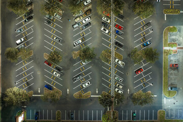 Aerial night view of many cars parked on parking lot with lines and markings for parking places and directions. Place for vehicles in front of a grocery mall store © bilanol