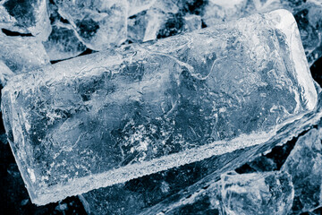 Textured, transparent rectangular ice block, on an ice surface. Cold freshness concept background.