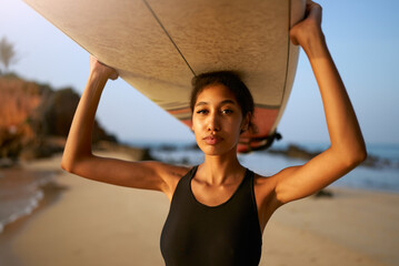 African american woman standing with surfboard on head on ocean beach. Black female surfer posing...