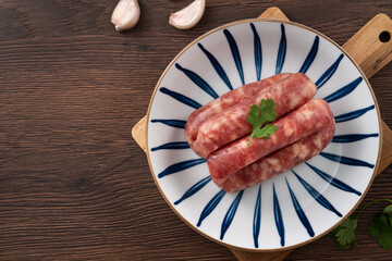 Raw Taiwanese sausage in garlic flavor in a plate on wooden table background.