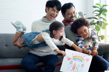 Male gay couple show their kid's family drawing, gay couple having fun with kids at home, LGBTQ...