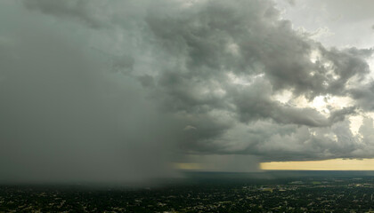 Dark stormy clouds forming on gloomy sky during heavy rainfall season over suburban town area