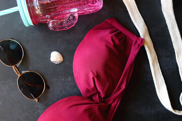 Pink bikini, cold soda, bag with peaches, sunglasses and little shell. Summer essentials on dark...