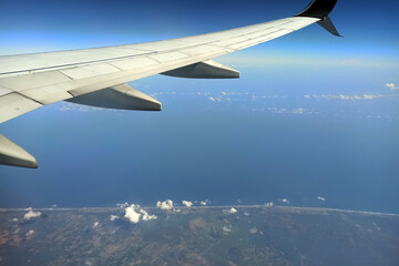View through airplane window of commercial jet plane wing flying high in the sky. Air travelling concept