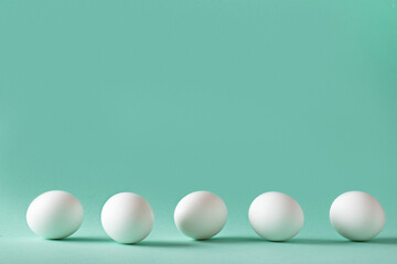 Five white eggs on a pale blue background