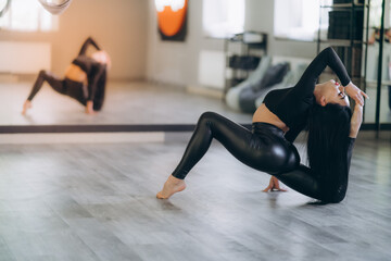 a charming girl in black sportswear, sitting on a longitudinal splits. Good stretching and gymnastics