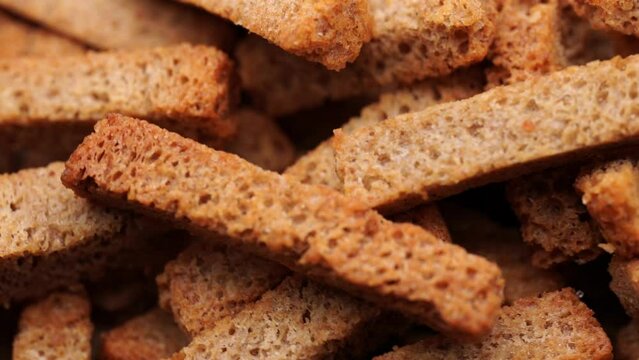 Crispy toasted bread croutons. A pile of hard rusks from dark dry bread close up. Snack for beer. Rye crackers. Snacks rye crackers in a strip. Crouton or brown roasted tostes rotating. 
